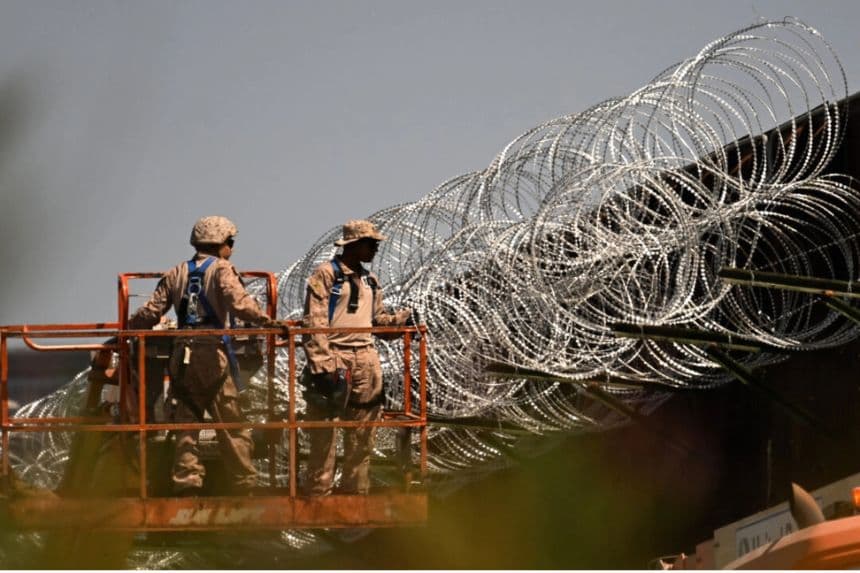 Personal militar estadounidense instala alambre de púas en la parte superior del muro que separa la frontera entre Estados Unidos y México, entre San Diego y Tijuana, cerca del puerto de entrada de San Ysidro, en San Diego, el 23 de abril de 2025. (Patrick T. Fallon/AFP a través de Getty Images)