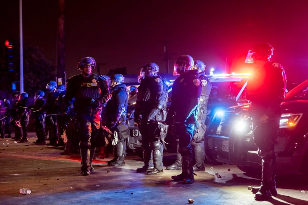 Agentes de las fuerzas del orden montan guardia frente a manifestantes durante una protesta tras una operación federal de inmigración en el barrio de Compton, en Los Ángeles, en la madrugada del 8 de junio de 2025. (Etienne Laurent/AFP a través de Getty Images)