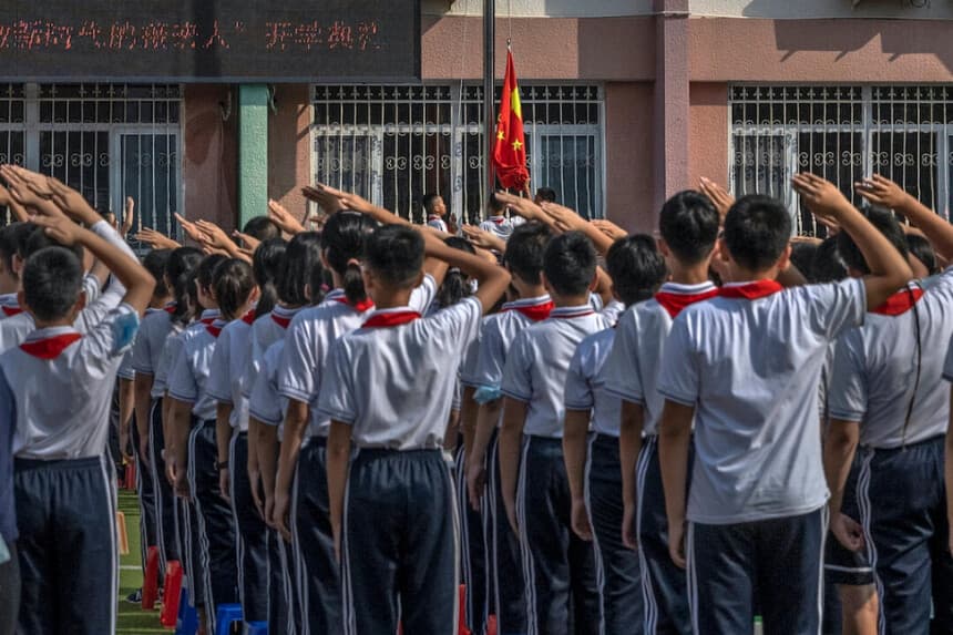 Alumnos saludan mientras se iza la bandera nacional de China durante una ceremonia celebrada el primer día del nuevo curso escolar en una escuela primaria de Beijing, China, el 1 de septiembre de 2021. Kevin Frayer/Getty Images