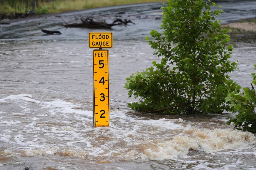 Un medidor de inundaciones marca la altura del agua que fluye sobre una carretera que conecta una granja con el mercado cerca de Kerrville, Texas, el 4 de julio de 2025. (Eric Gay/AP Photo).