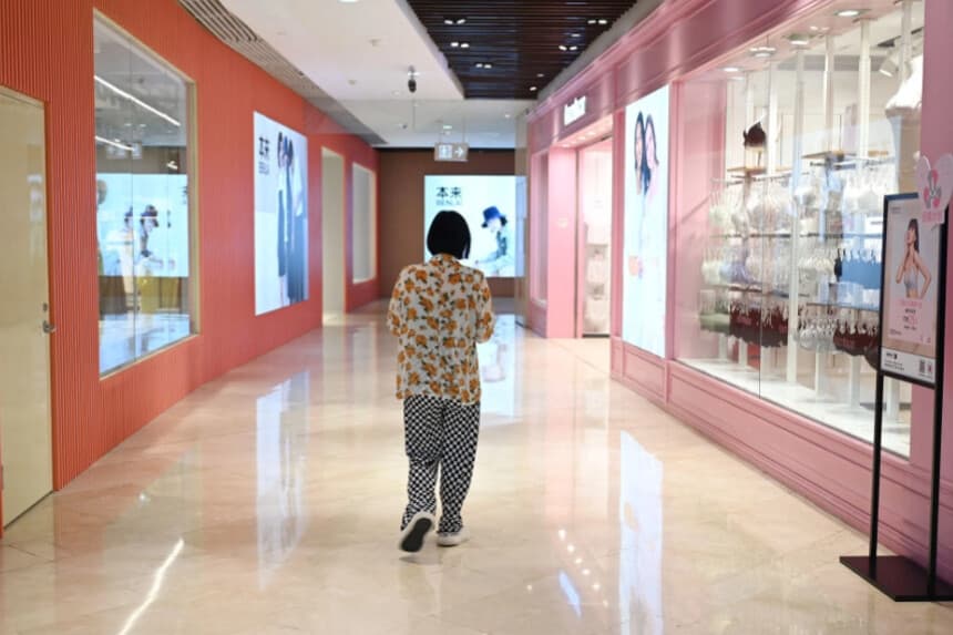 Una mujer pasa por delante de unas tiendas en un centro comercial de Beijing el 18 de julio de 2023. (Greg Baker/AFP a través de Getty Images).