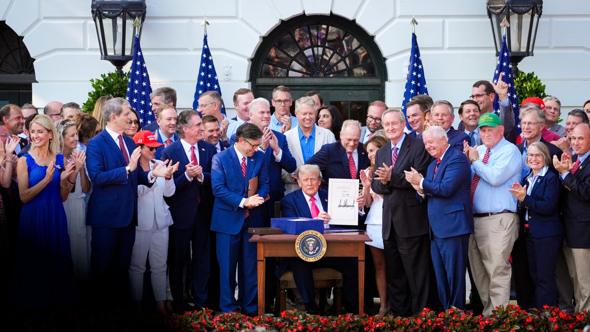 El presidente Donald Trump firma su emblemático proyecto de ley de recortes fiscales y recortes del gasto, rodeado de miembros del Congreso, en la Casa Blanca el 4 de julio de 2025. Además de importantes cambios en el código tributario, la legislación incluye disposiciones que afectan a los viajes, la atención sanitaria de las mujeres, la inmigración y los programas de bienestar social. (Evan Vucci/Foto de AP)