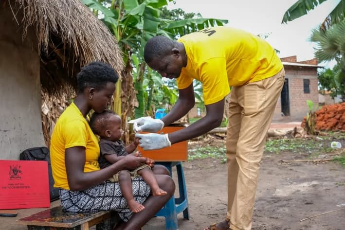 Un funcionario sanitario toma una muestra de sangre a un bebé para realizar una prueba rápida de diagnóstico de la malaria después de informar a los miembros de la comunidad sobre la vacuna contra la malaria en el distrito de Apac, Uganda, el 7 de abril de 2025. (Hajarah Nalwadda/Getty Images)
