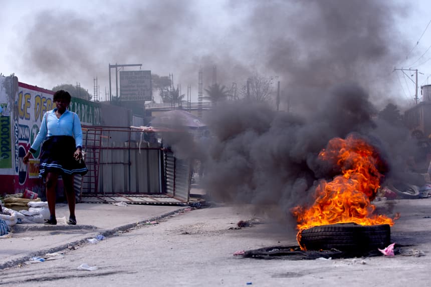 Fotografía de archivo, tomada el pasado 24 de abril, de una mujer al caminar cerca de una barricada en la zona de Tabarre, durante una jornada de movilizaciones contra la inseguridad, en Puerto Príncipe, Haití. (EFE/Mentor David Lorens)