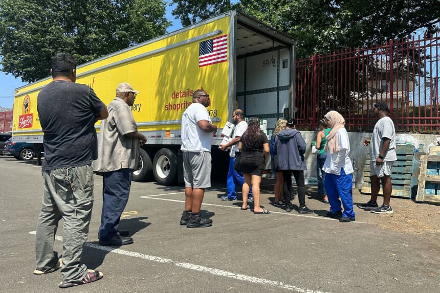 Personas afectadas por una rotura en la tubería principal que provocó la interrupción del servicio en casi 200,000 hogares y negocios recogen cajas de agua embotellada en la escuela secundaria John F. Kennedy de Paterson, Nueva Jersey, el 11 de agosto de 2025. (Ted Shaffrey/AP Photo).