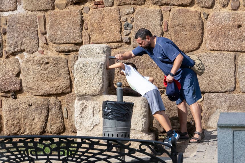 Un padre ayuda a su hijo a beber agua de una fuente en España. (EFE/ Jero Morales)