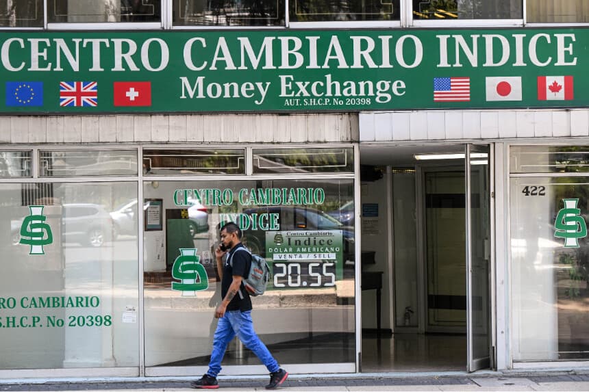 Un hombre pasa frente a una casa de cambio con los tipos de cambio en la Ciudad de México el 7 de abril de 2025. Mientras que el dólar estadounidense se recuperó tras las fuertes pérdidas de la semana pasada, los mercados bursátiles y los precios del petróleo en todo el mundo se desplomaron aún más en un lunes negro para los mercados, ya que el presidente de Estados Unidos, Donald Trump, se mantuvo firme en sus aranceles a pesar de los temores de recesión. (Foto de YURI CORTEZ/AFP a través de Getty Images).