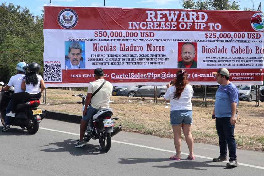Personas observan una valla con la imagen del presidente de Venezuela, Nicolás Maduro, y del ministro de Relaciones Interiores, Justicia y Paz de Venezuela, Diosdado Cabello, este sábado en Villa del Rosario, Colombia. (EFE/ Mario Caicedo)