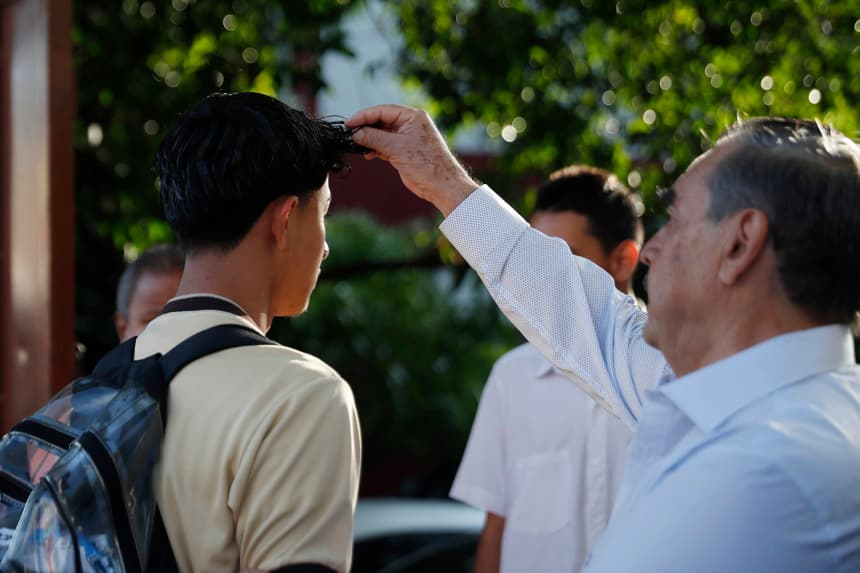 Un docente recibe a estudiantes del Instituto Nacional "General Manuel José Arce" este lunes, en San Salvador (EFE/Rodrigo Sura)