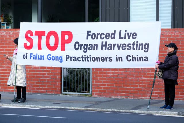 Manifestantes sostienen una pancarta frente a la Casa de Gobierno antes de la ceremonia oficial de bienvenida al primer ministro del PCCh, Li Qiang, en Wellington, Nueva Zelanda, el 13 de junio de 2024. Hagen Hopkins/Getty Images