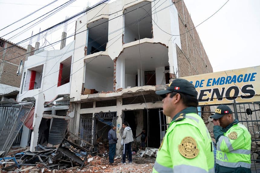 Agentes de policía montan guardia frente a los restos de una casa que sufrió un ataque con dinamita causado por enfrentamientos entre organizaciones criminales en la ciudad de Trujillo, al norte de Perú, el 15 de agosto de 2025. (Foto de STRINGER/AFP a través de Getty Images)