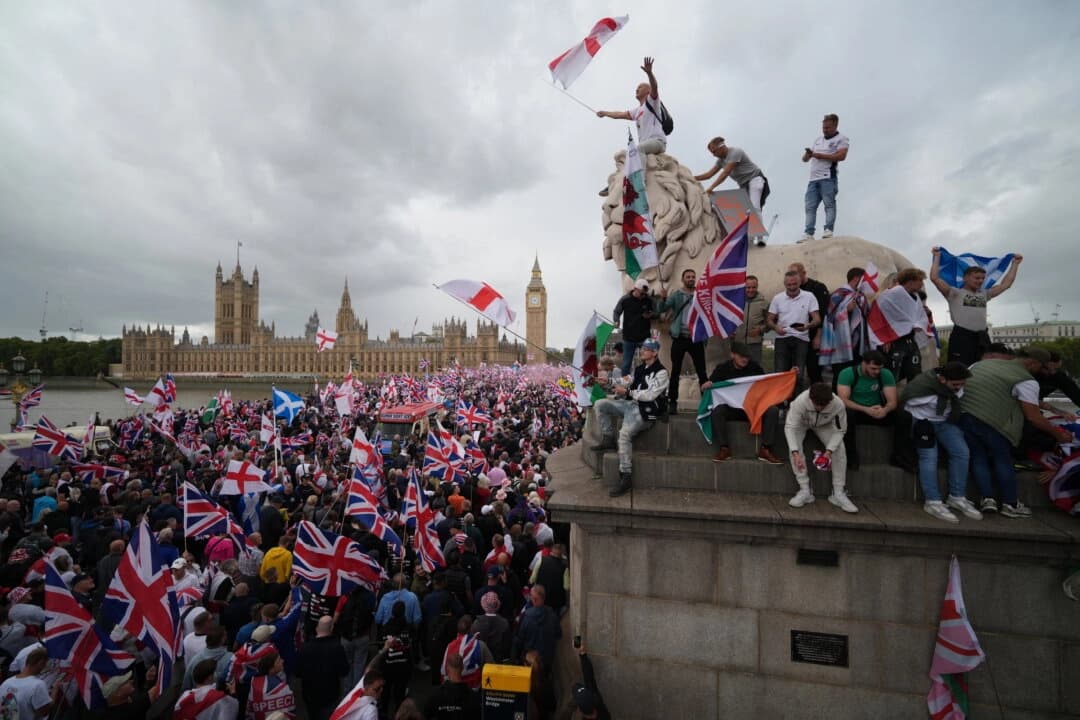 Los manifestantes ondean banderas de la Unión Jack y de San Jorge de Inglaterra durante la manifestación "Unir El Reino" en el puente de Westminster, junto al Parlamento de Londres, el 13 de septiembre de 2025. (Christopher Furlong/Getty Images)