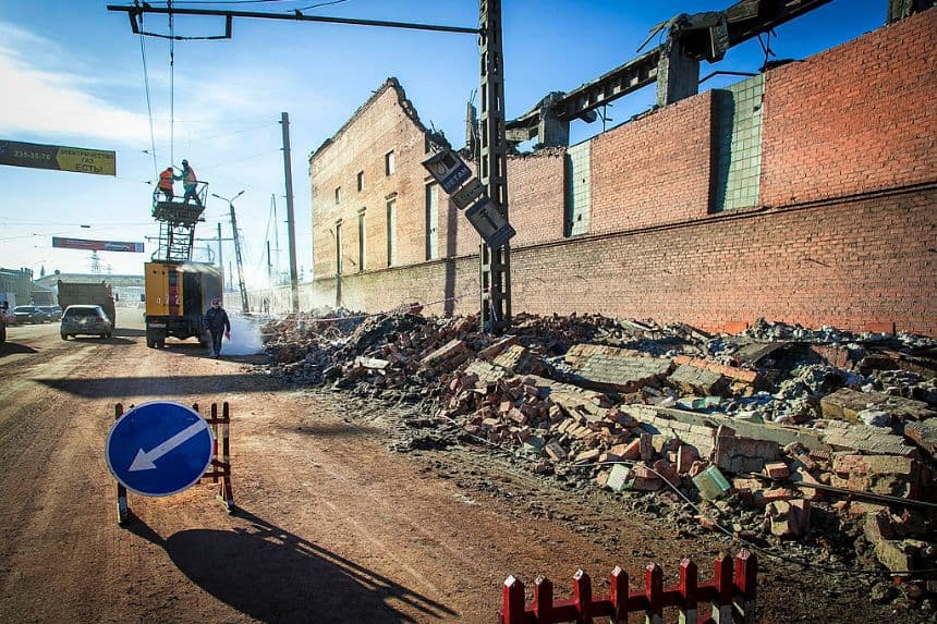 Trabajadores reparan una línea eléctrica cerca de la pared de una planta local de zinc que fue dañada por la onda expansiva del meteorito en la ciudad de Chelyabinsk, en los Urales, el 15 de febrero de 2013. (OLEG KARGOPOLOV/AFP a través de Getty Images)