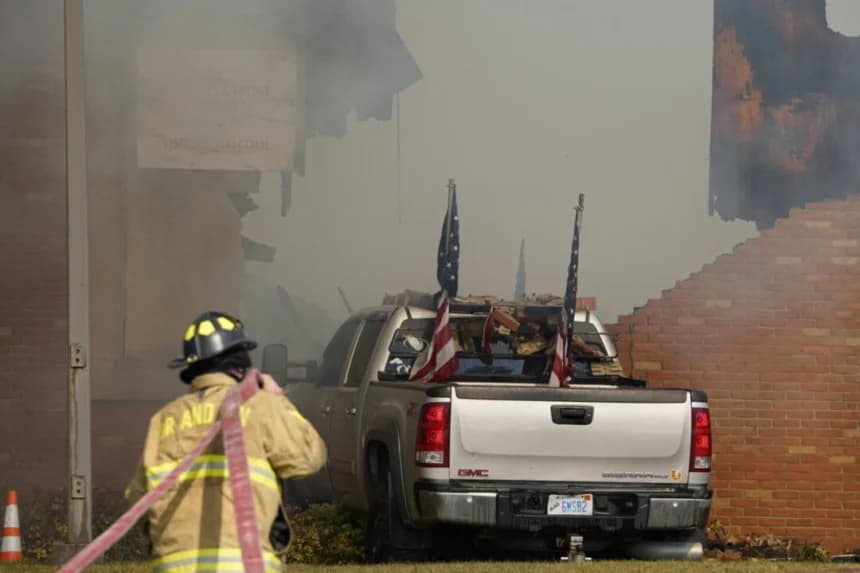 Un vehículo que fue estrellado contra el edificio es rodeado por humo mientras un bombero trabaja en la escena en la Iglesia de Jesucristo de los Santos de los Últimos Días en Grand Blanc, Michigan, el 28 de septiembre de 2025. (Lukas Katilius/The Flint Journal vía AP)