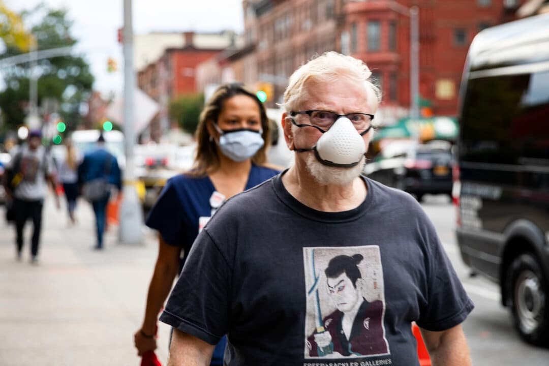 Personas con mascarillas protectoras caminan por la calle en una foto de archivo. (Chung I Ho/The Epoch Times)