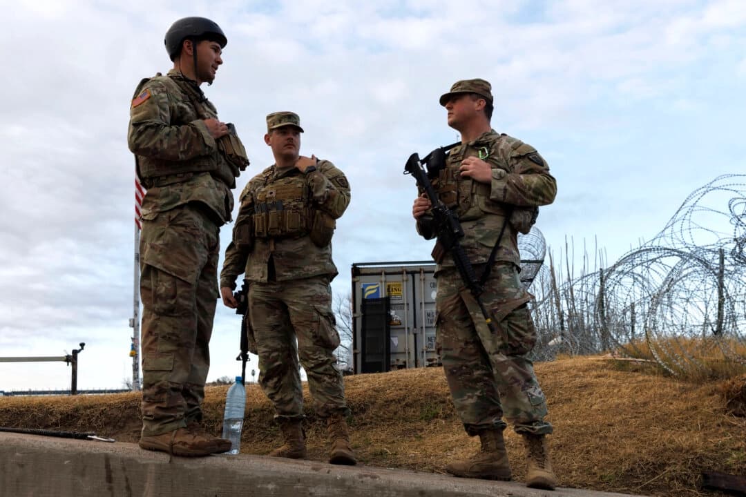 Soldados de la Guardia Nacional de Texas esperan cerca de la rampa para embarcaciones donde las fuerzas del orden entran en el Río Grande en Shelby Park, en Eagle Pass, Texas, el 26 de enero de 2024. (Michael Gonzalez/Getty Images)