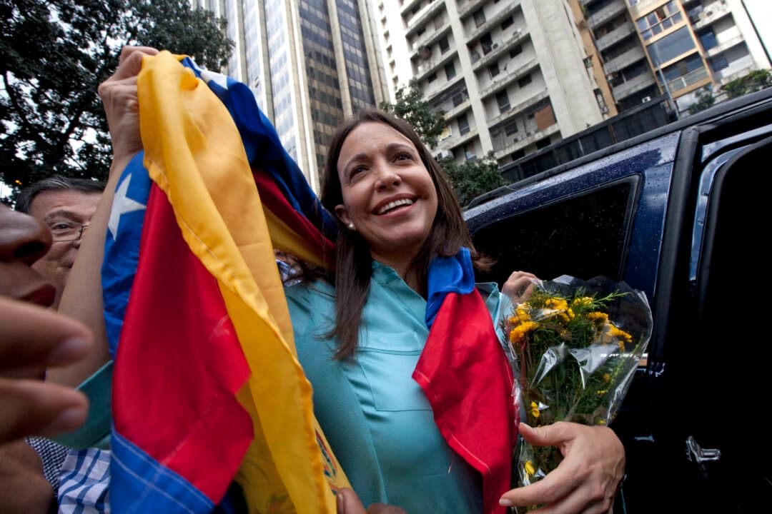 La exdiputada y líder de la oposición María Corina Machado sostiene la bandera venezolana frente a la Fiscalía General en Caracas, Venezuela, el 3 de diciembre de 2014. (Ariana Cubillos/AP Photo)