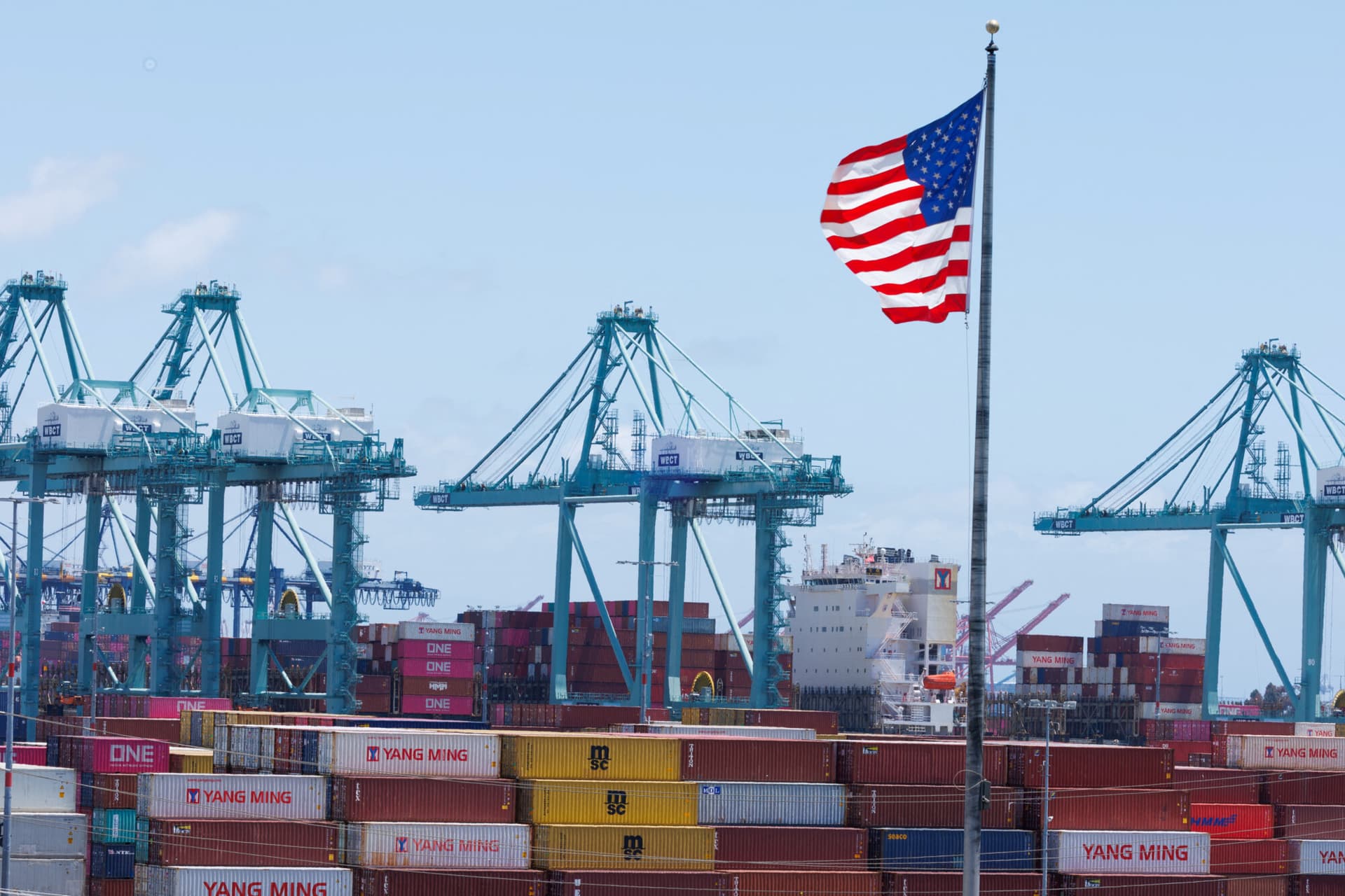 Una bandera estadounidense ondea sobre los contenedores de transporte en el puerto de Los Ángeles, en San Pedro, California, el 13 de mayo de 2025. (Mike Blake/Reuters)