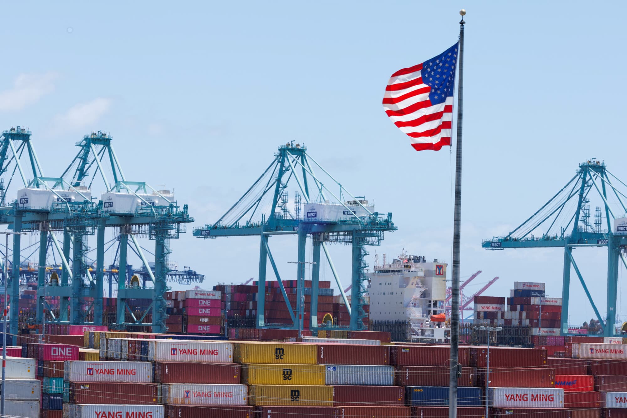Una bandera estadounidense ondea sobre los contenedores de transporte en el puerto de Los Ángeles, en San Pedro, California, el 13 de mayo de 2025. (Mike Blake/Reuters)