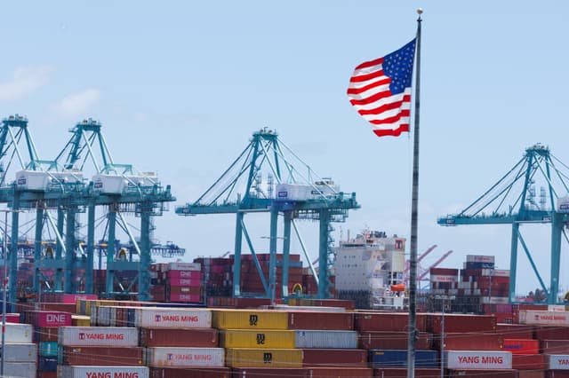 Una bandera estadounidense ondea sobre los contenedores de transporte en el puerto de Los Ángeles, en San Pedro, California, el 13 de mayo de 2025. (Mike Blake/Reuters)