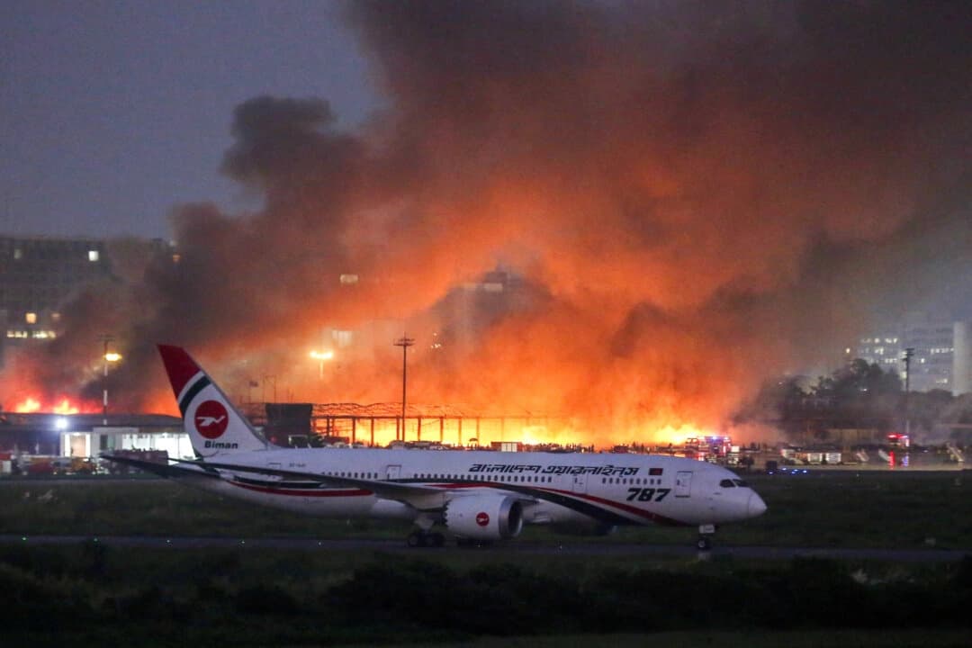 Un avión de pasajeros permanece en la pista, mientras el humo se eleva tras el incendio que se produjo en la bodega de carga del Aeropuerto Internacional Hazrat Shahjalal, en Daca, Bangladés, el 18 de octubre de 2025. (Mehedi Hasan/Reuters)