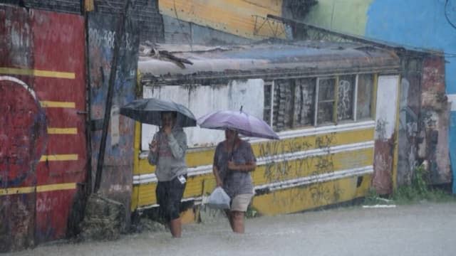 La gente camina por una calle inundada por las lluvias causadas por la tormenta tropical Melissa en Santo Domingo, República Dominicana, el 24 de octubre de 2025. (Ricardo Hernández/AP Photo)
