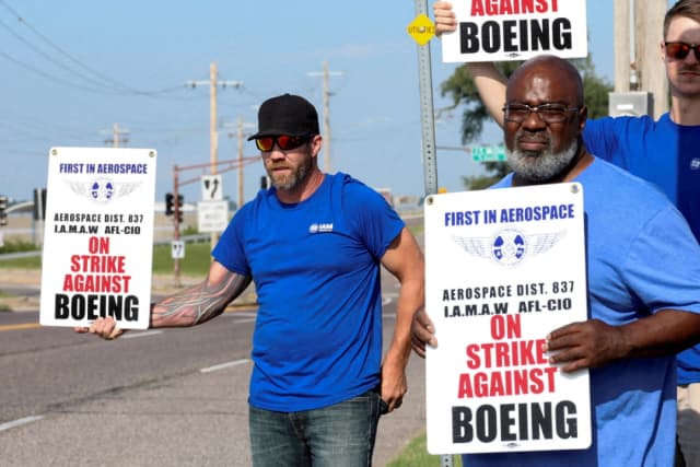 Los trabajadores sostienen pancartas durante una huelga de los miembros de la Asociación Internacional de Maquinistas y Trabajadores Aeroespaciales por las negociaciones del contrato, frente a las instalaciones de la empresa Boeing en Berkeley, Misuri, el 4 de agosto de 2025. (Lawrence Bryant/Reuters).