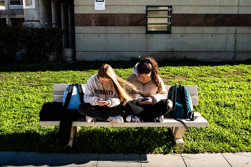 Adolescentes sentadas en un banco durante el receso y consultando sus teléfonos o smartphones y redes sociales en el Liceo Aristide Maillol de Perpiñán, en el departamento de Pirineos Orientales, al sur de Francia, el 14 de noviembre de 2024. (JC MILHET/Hans Lucas/AFP vía Getty Images)