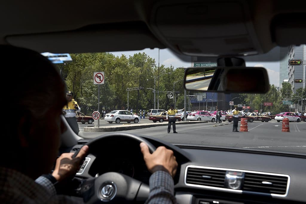 Un conductor de la empresa privada de taxis Uber es desviado por la policía de tránsito de la avenida Insurgentes mientras los taxistas cruzan la avenida durante protesta contra la empresa por supuesta competencia desleal, en la Ciudad de México, el 25 de mayo de 2015.  (YURI CORTEZ/AFP a través de Getty Images)