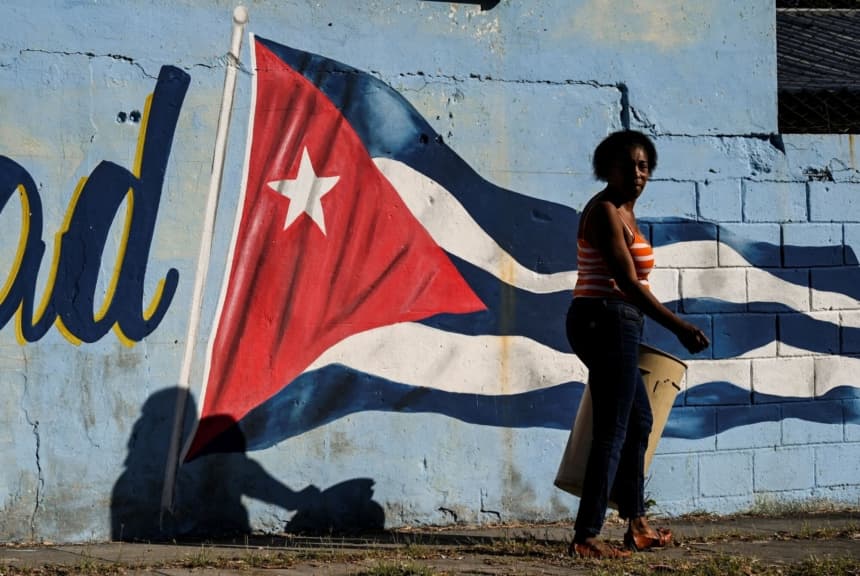 Una mujer pasa frente a un muro pintado con la bandera cubana que dice "Continuidad" en La Habana el 7 de febrero de 2023. (YAMIL LAGE/AFP via Getty Images)