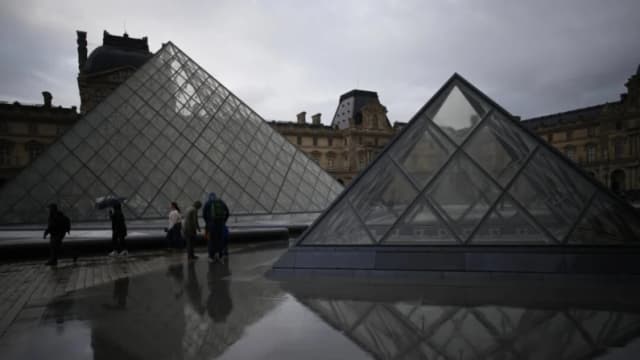 Visitantes recorren el patio del museo del Louvre bajo la lluvia en París, el 27 de octubre de 2025. (Foto: Christophe Ena/AP)