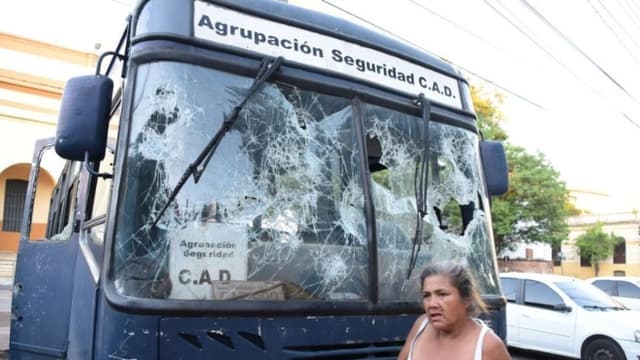 Una mujer camina junto a un autobús cuyas ventanas se encuentran destrozadas en Asunción, el 6 de marzo de 2021. (NORBERTO DUARTE/AFP via Getty Images)