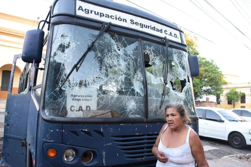 Una mujer camina junto a un autobús cuyas ventanas se encuentran destrozadas en Asunción, el 6 de marzo de 2021. (NORBERTO DUARTE/AFP via Getty Images)