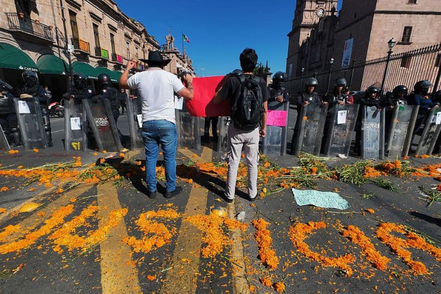 Manifestantes protestan contra el asesinato del alcalde de Uruapan frente a agentes de policía en el Palacio de Gobierno de Morelia, estado de Michoacán, México, el 3 de noviembre de 2025. (JORDI LEBRIJA/AFP a través de Getty Images)