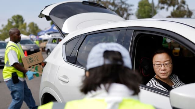 Voluntarios entregan cajas de alimentos a personas en una distribución de alimentos a gran escala, en respuesta al cierre del gobierno federal y los retrasos en los beneficios alimentarios SNAP/CalFresh, el 5 de noviembre de 2025 en la ciudad de Industry, California. (Mario Tama/Getty Images)