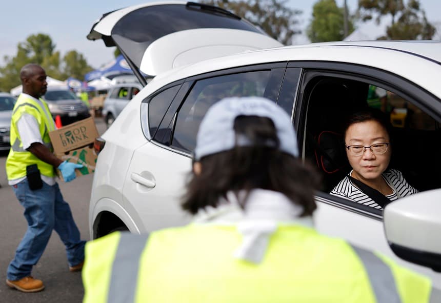Voluntarios entregan cajas de alimentos a personas en una distribución de alimentos a gran escala, en respuesta al cierre del gobierno federal y los retrasos en los beneficios alimentarios SNAP/CalFresh, el 5 de noviembre de 2025 en la ciudad de Industry, California. (Mario Tama/Getty Images)