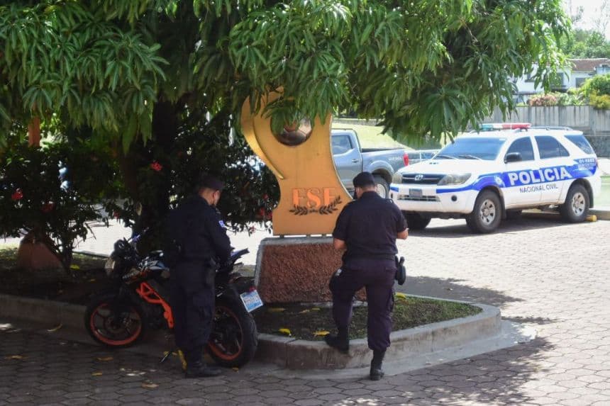 Agentes de policía son fotografiados en el estacionamiento de las instalaciones de la Federación Salvadoreña de Fútbol (FESFUT) en San Salvador, el 14 de julio de 2022. La Fiscalía General de El Salvador inició el jueves una redada en las instalaciones de la Federación Salvadoreña de Fútbol (FESFUT), como parte de una investigación sobre un presunto delito de lavado de dinero, según informó el organismo judicial.(STHANLY ESTRADA/AFP vía Getty Images)