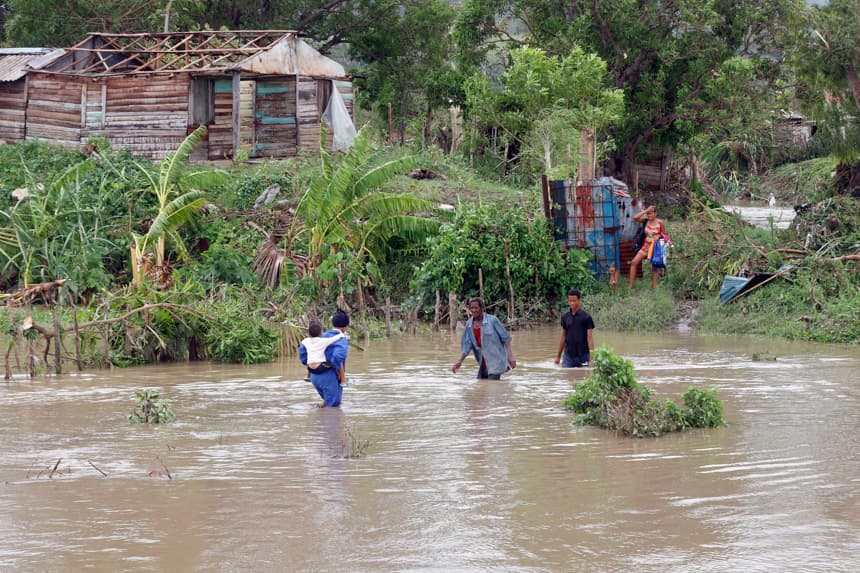 Personas cruzan un río crecido este miércoles, en el poblado de Guama en Santiago de Cuba, Cuba. (EFE/ Ernesto Mastrascusa)
