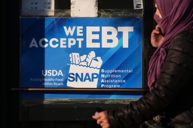 Un cartel informativo sobre el programa SNAP EBT se exhibe en una panadería mientras una mujer pasa por delante en Chicago el 2 de noviembre de 2025. (Nam Y. Huh/Foto de AP)