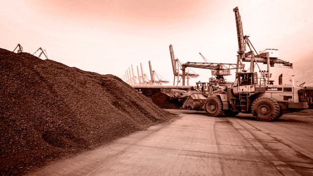 Un hombre maniobra una pala cargadora para remover tierra con minerales de tierras raras para la exportación a Japón en un puerto de Lianyungang, provincia de Jiangsu, China, el 5 de septiembre de 2010. China ostenta un cuasi monopolio sobre la industria de las tierras raras, desde la extracción y el refinado hasta la fabricación de imanes. (Editado por The Epoch Times, STR/AFP vía Getty Images)