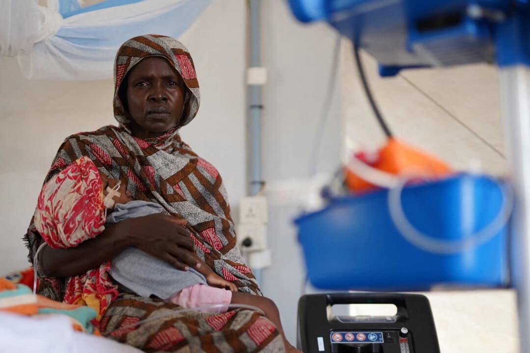 Una mujer sudanesa desplazada y herida que huyó de la violencia en Al-Fashir recibe tratamiento mientras lleva a su hijo en brazos en una clínica improvisada gestionada por Médicos Sin Fronteras (MSF), en medio de los continuos enfrentamientos entre las Fuerzas de Apoyo Rápido (RSF) paramilitares y el ejército sudanés, en Tawila, Darfur del Norte, Sudán, el 3 de noviembre de 2025. (REUTERS/Mohamed Jamal)