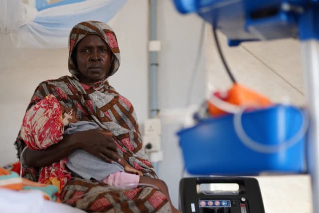 Una mujer sudanesa desplazada y herida que huyó de la violencia en Al-Fashir recibe tratamiento mientras lleva a su hijo en brazos en una clínica improvisada gestionada por Médicos Sin Fronteras (MSF), en medio de los continuos enfrentamientos entre las Fuerzas de Apoyo Rápido (RSF) paramilitares y el ejército sudanés, en Tawila, Darfur del Norte, Sudán, el 3 de noviembre de 2025. (REUTERS/Mohamed Jamal)