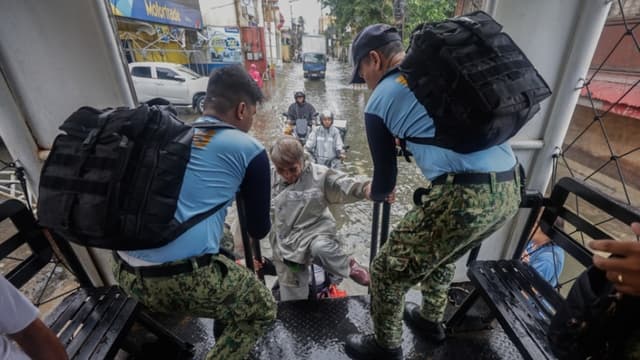 La policía filipina, en un camión que ofrece transporte gratuito, ayuda a un residente en un distrito inundado debido a la marea alta y las marejadas ciclónicas en las zonas costeras, causadas por el tifón Fung-Wong en la ciudad de Navotas, Metro Manila, Filipinas, el 10 de noviembre de 2025. (EFE/EPA/ROLEX DELA PENA)