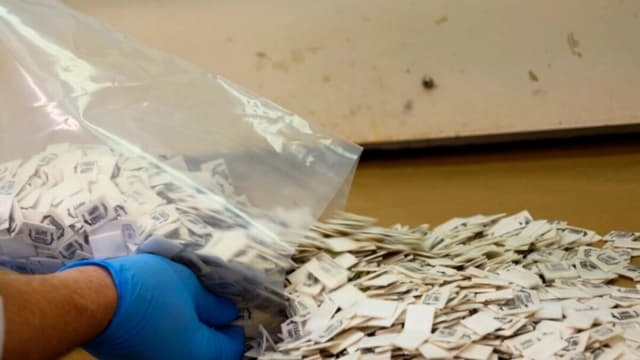 Un experto de la Administración para el Control de Drogas (DEA) vierte 2500 paquetes de fentanilo confirmado sobre una superficie para su análisis en el Laboratorio Regional Noreste de la DEA en la ciudad de Nueva York, el 8 de octubre de 2019. (Don Emmert/AFP vía Getty Images)