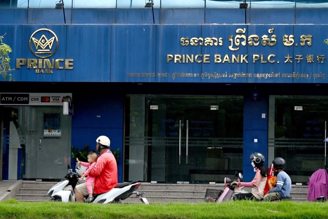 Automovilistas pasan frente a una sucursal del Prince Bank en Phnom Penh, Camboya, el 15 de octubre de 2025. El banco forma parte de Prince Holding Group, un conglomerado multinacional fundado por Chen Zhi que, según el Departamento de Justicia de EE. UU., sirvió de fachada para "una de las mayores organizaciones criminales transnacionales de Asia". (Tang Chhin Sothy/AFP)