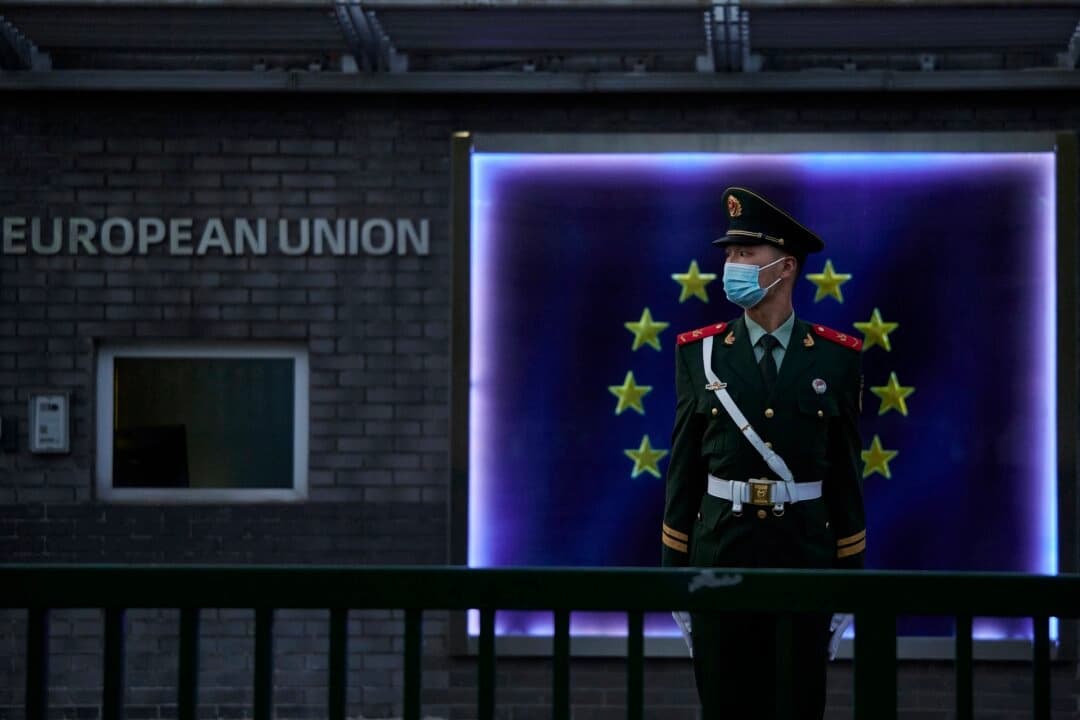 Un miembro de la Policía Armada Popular monta guardia frente a la bandera de la Unión Europea en la Delegación Europea antes de una rueda de prensa de la presidenta de la Comisión Europea, Ursula von der Leyen, en Beijing, el 6 de abril de 2023. (Kevin Frayer/Getty Images)