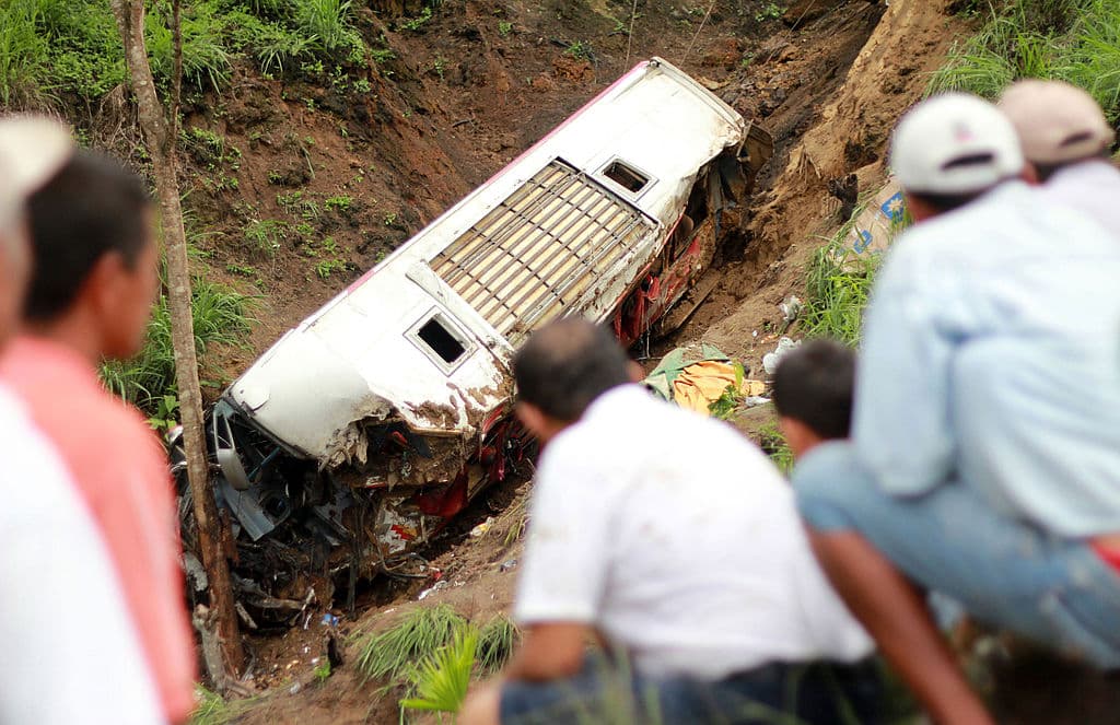 La gente observa los restos de un autobús que cayó a un profundo barranco al descender cerca de La Crespa, cuando viajaba desde la capital, Quito, hacia las localidades orientales de Chone y San Isidro, el 24 de diciembre de 2010. (Rodolfo Parraga/AFP a través de Getty Images).