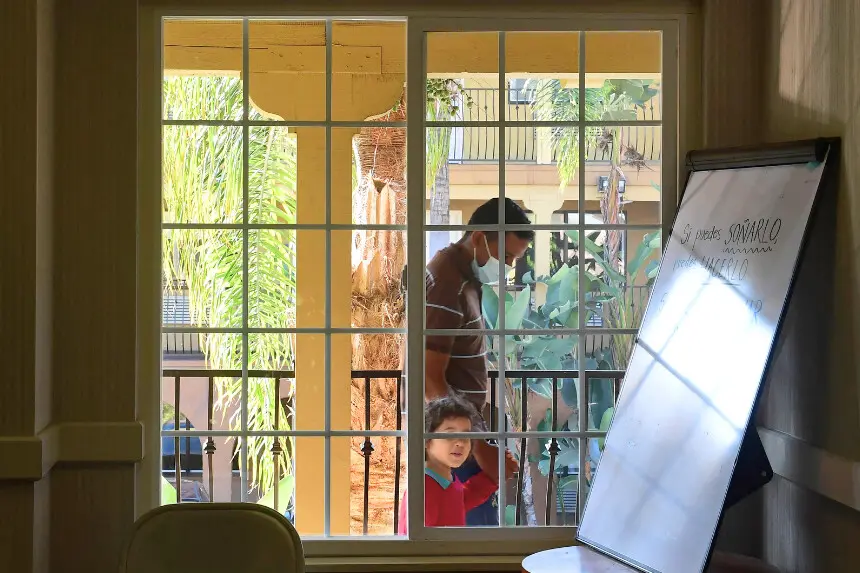 Un padre y su hijo salen de una oficina de admisión y tramitación en un refugio para migrantes gestionado por organizaciones benéficas católicas en San Diego, California, el 9 de noviembre de 2021, un día después de que se reabriera la frontera entre Estados Unidos y México, de casi 3200 kilómetros, tras 20 meses de cierre por la COVID-19. (Foto de FREDERIC J. BROWN/AFP a través de Getty Images)