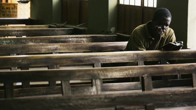 Un fiel nigeriano lee su Biblia después de que otros miembros de la parroquia se hayan retirado en Kano, Nigeria.(Photo by Chris Hondros/Getty Images)