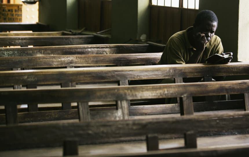 Un fiel nigeriano lee su Biblia después de que otros miembros de la parroquia se hayan retirado en Kano, Nigeria.(Photo by Chris Hondros/Getty Images)